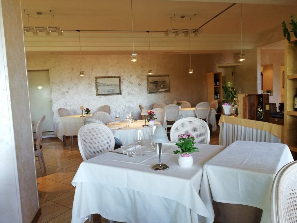 Interno del ristorante con tovaglie, sedie e decorazioni bianche.