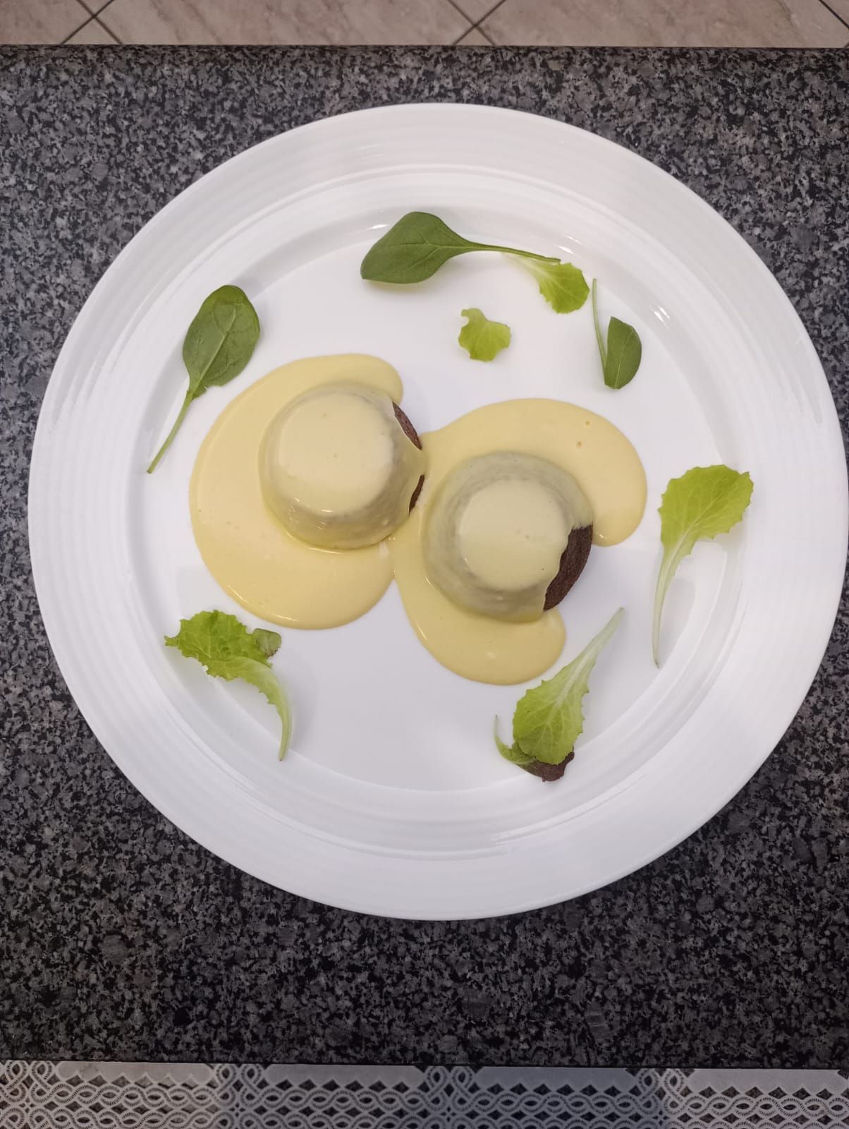 Piatto elegante con due cappelli di funghi, salsa gialla e guarnizione di foglie verdi.
