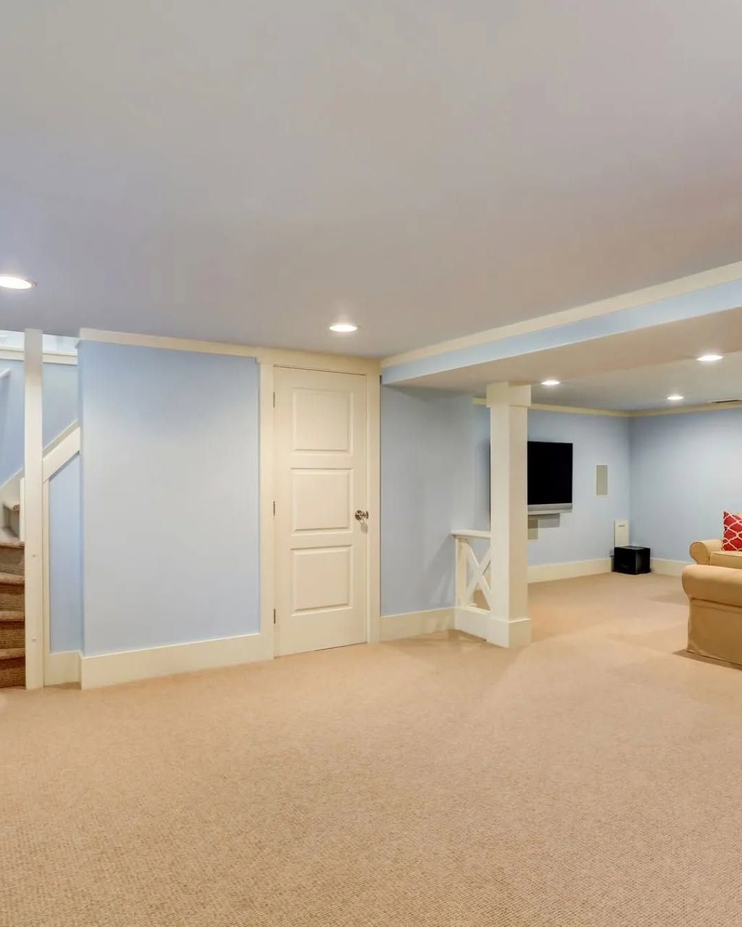 Empty carpeted living room with light blue walls, white trim, and recessed lighting