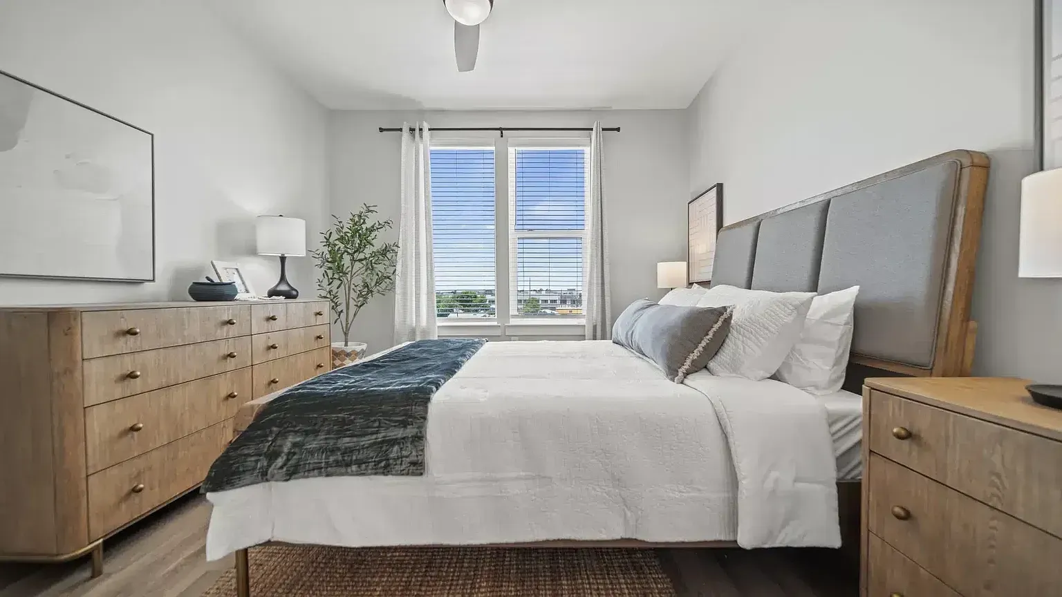 Modern bedroom with a king-size bed, dresser, and window view.