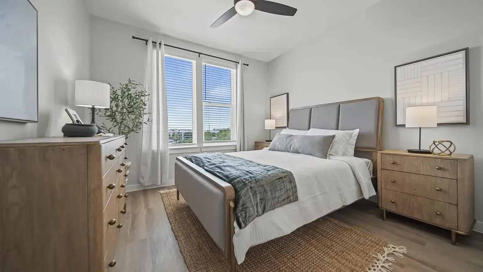 A spacious bedroom with a king-sized bed, dresser, nightstand, and a ceiling fan.