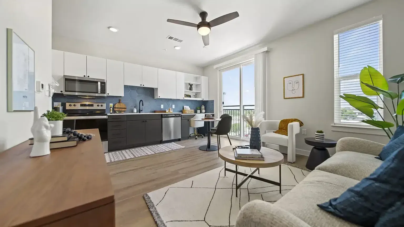 Open concept living area and kitchen with modern furnishings and a ceiling fan.
