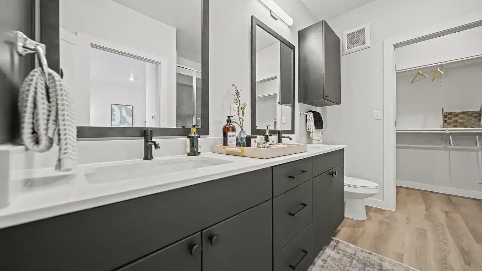 Modern double vanity bathroom with ample storage and a walk-in closet.