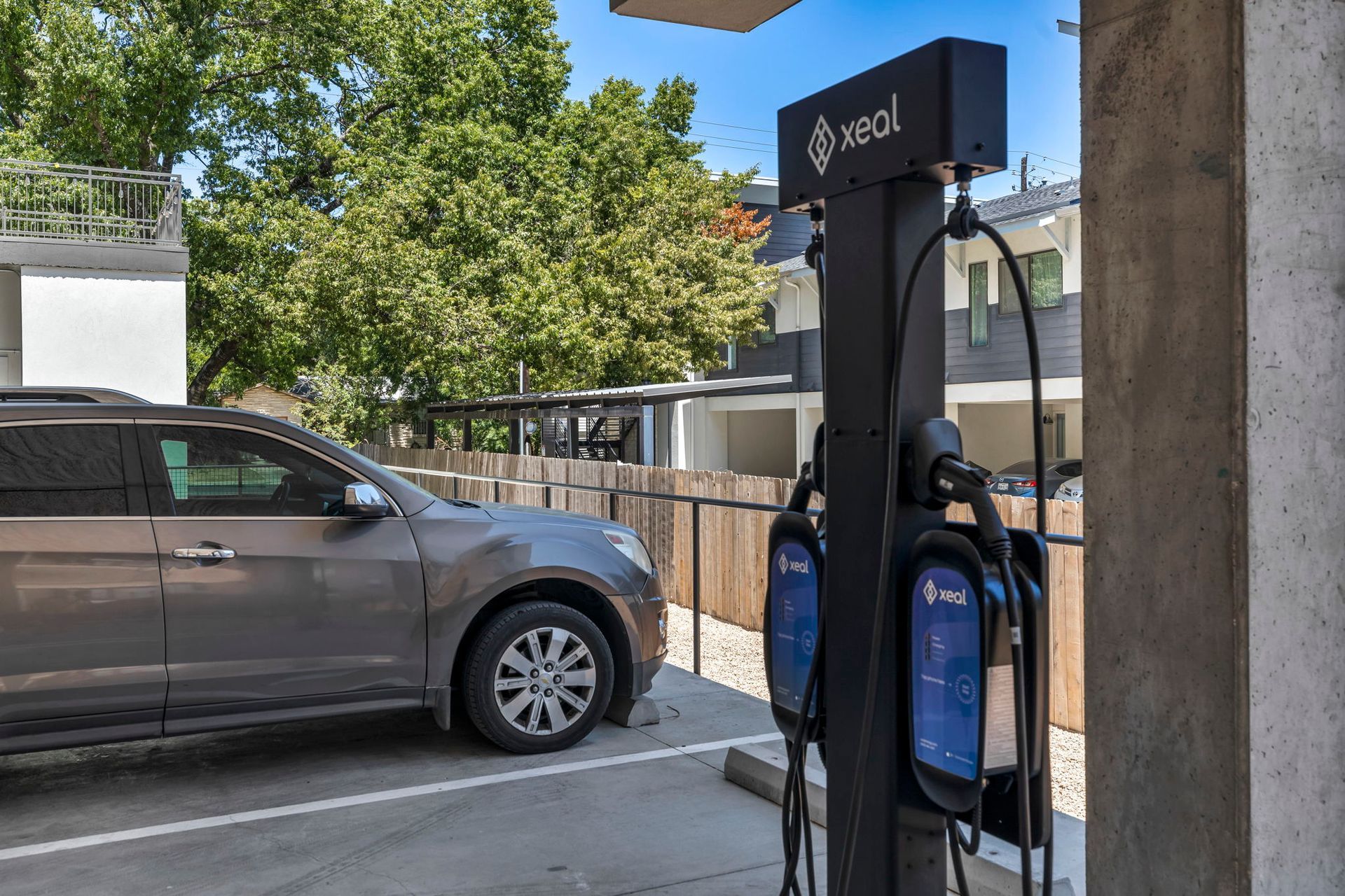 Gray SUV parked beside a blue EV charging station under a covered area