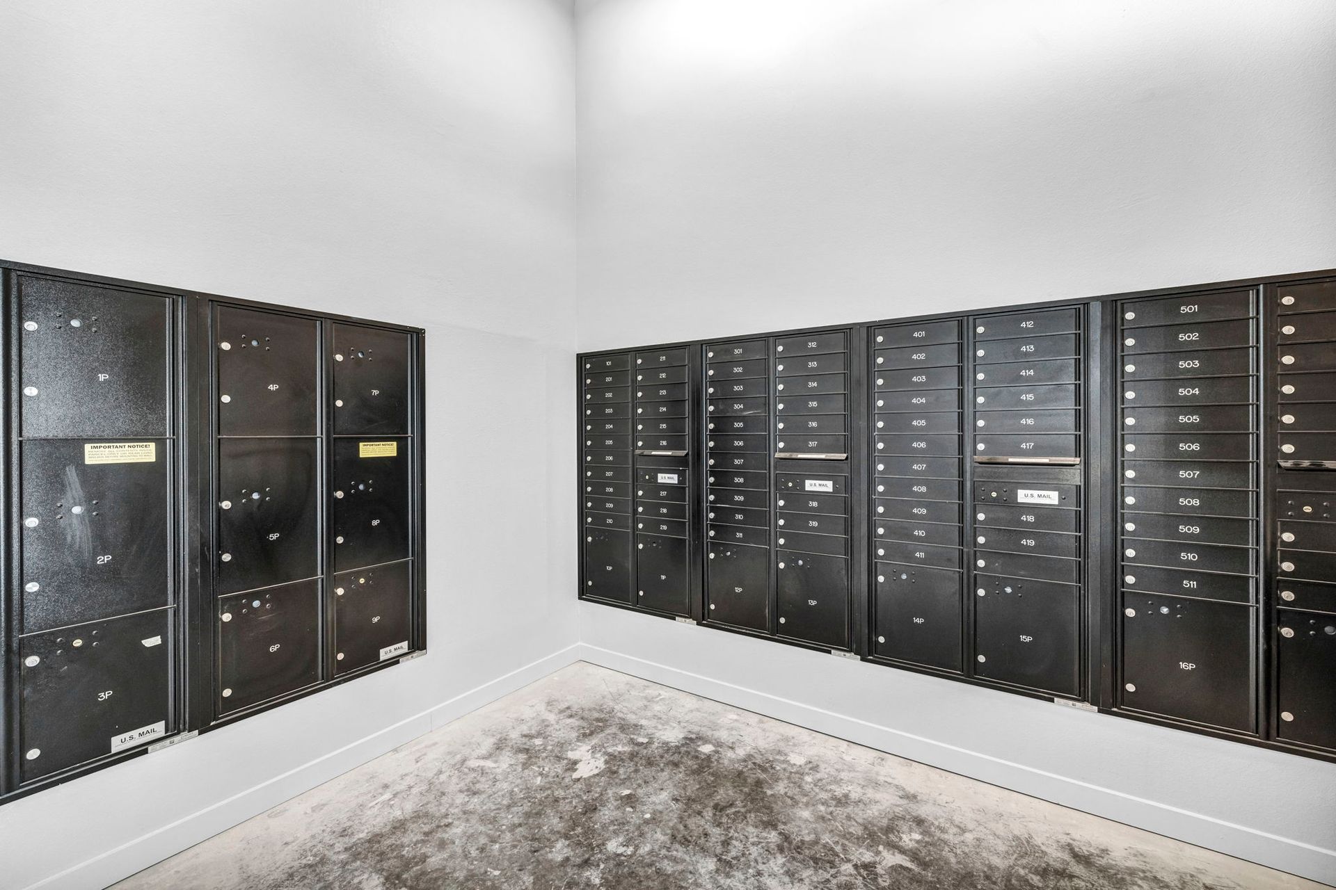 Rows of black mailboxes lining a bright white room with a concrete floor