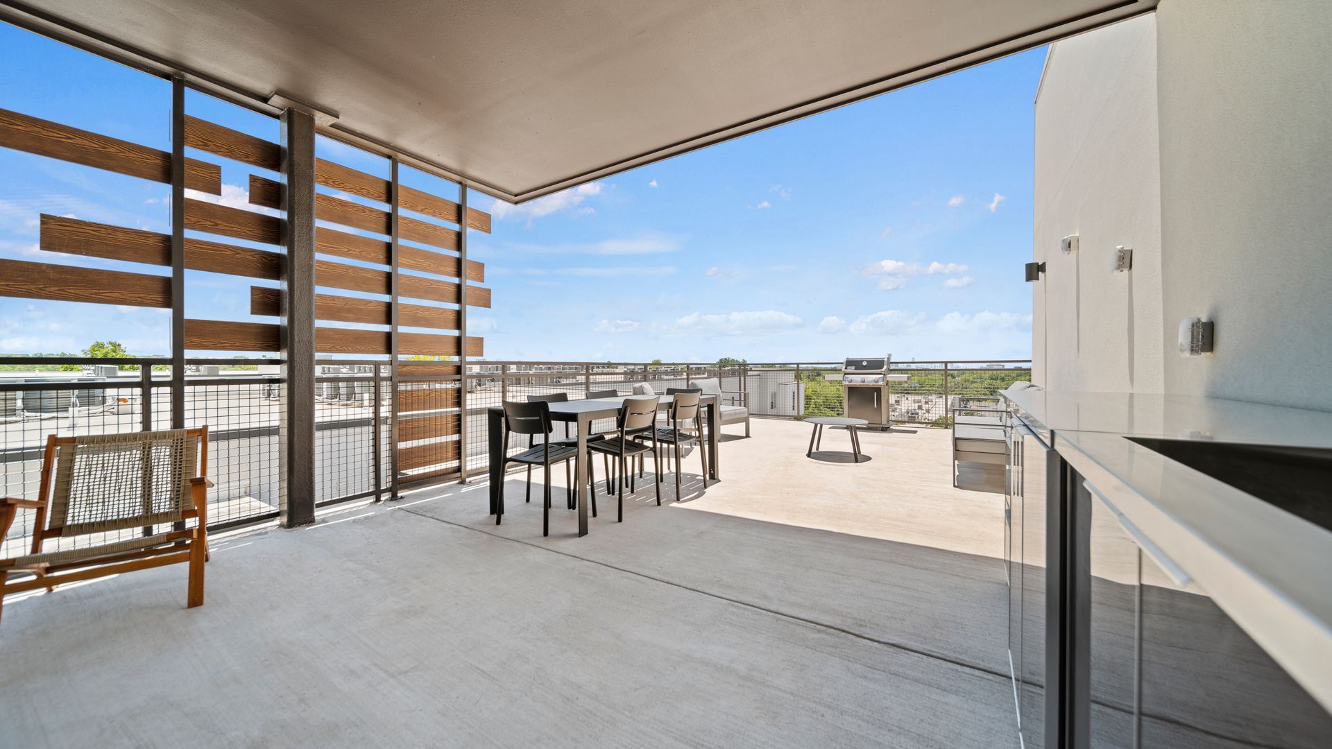 Spacious rooftop terrace with outdoor dining set, lounge chairs, and open sky view.