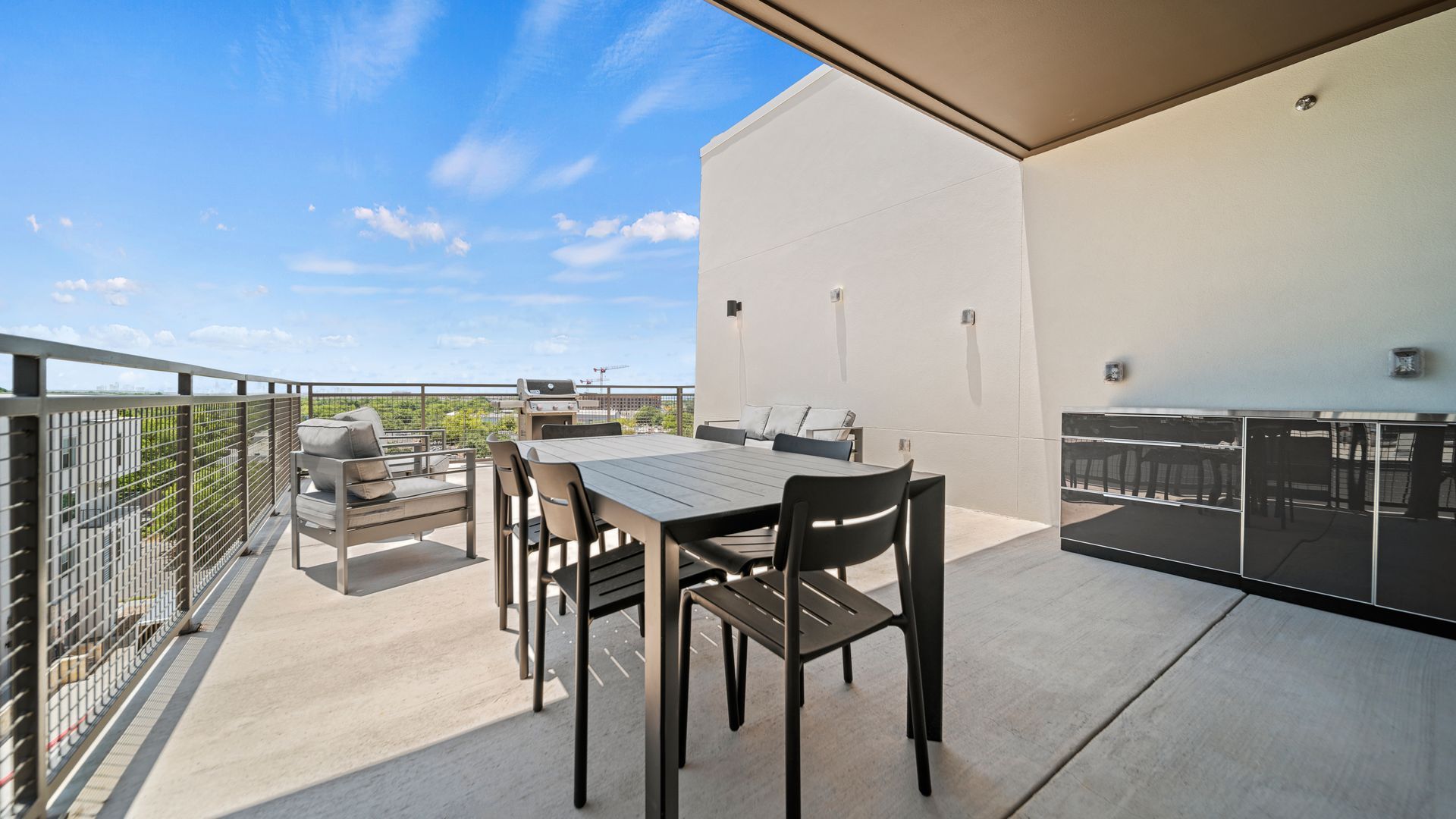 Balcony patio with table, chairs, grill, and city view under a covered roof