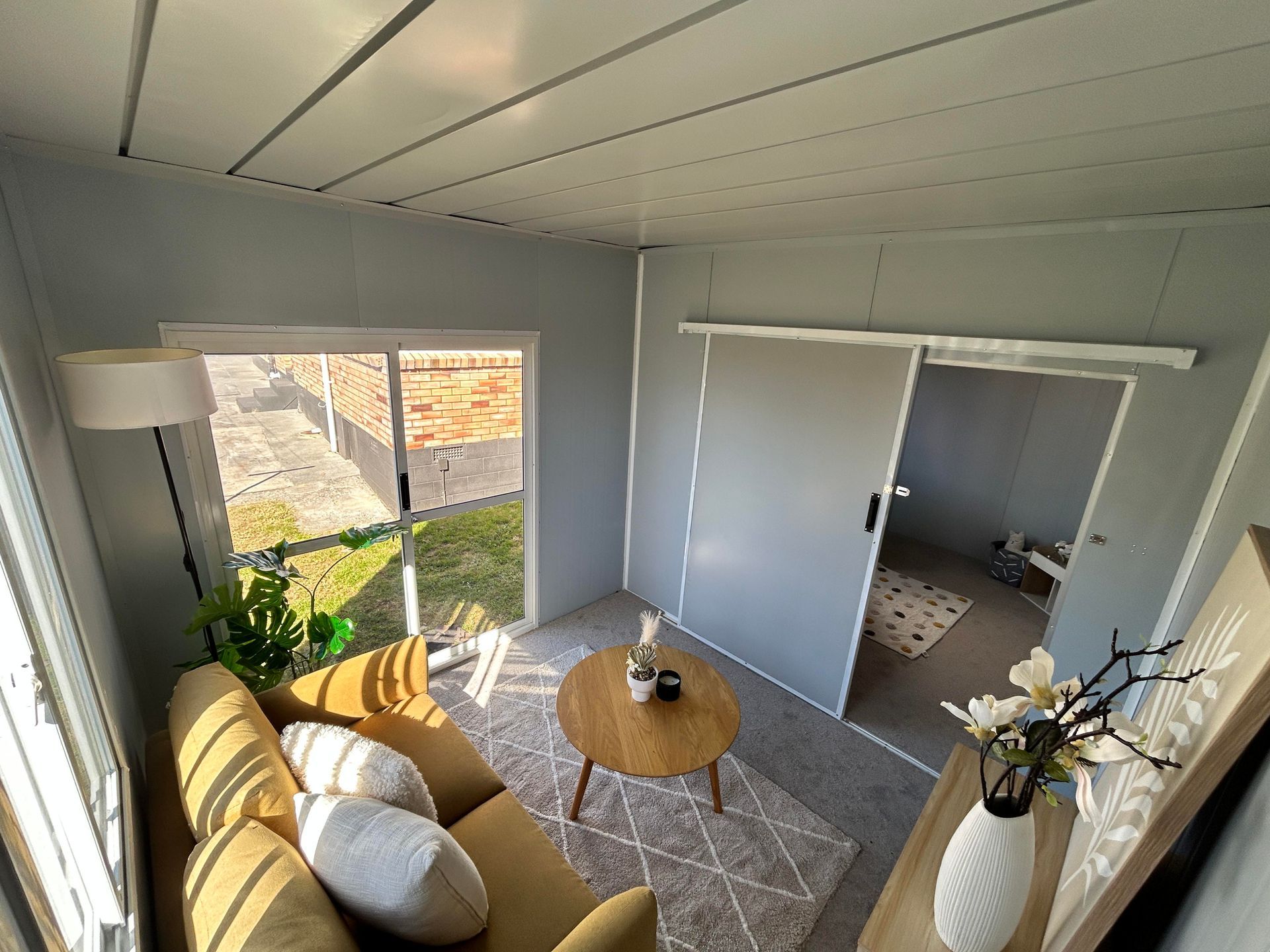 Bright living room with yellow chair, round table, sliding closet doors, and large window overlooking outdoors