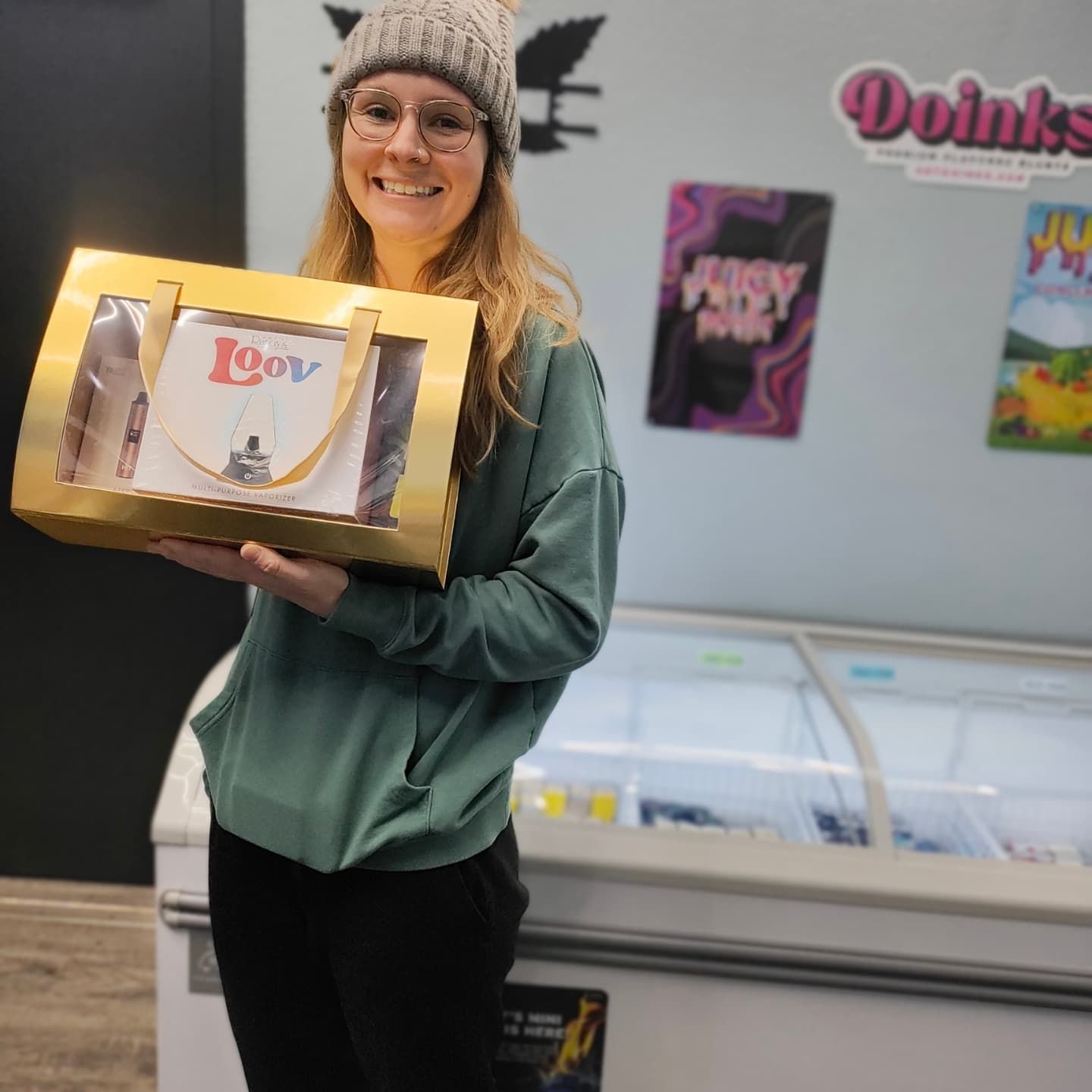 Woman smiling, holding a gold gift bag with a book inside, standing in front of a freezer.