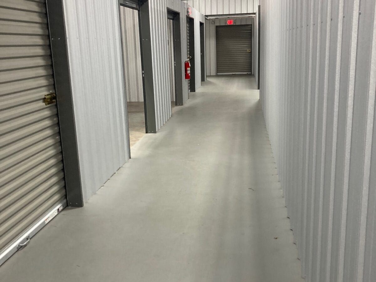 A long hallway with a lot of doors and a red exit sign.