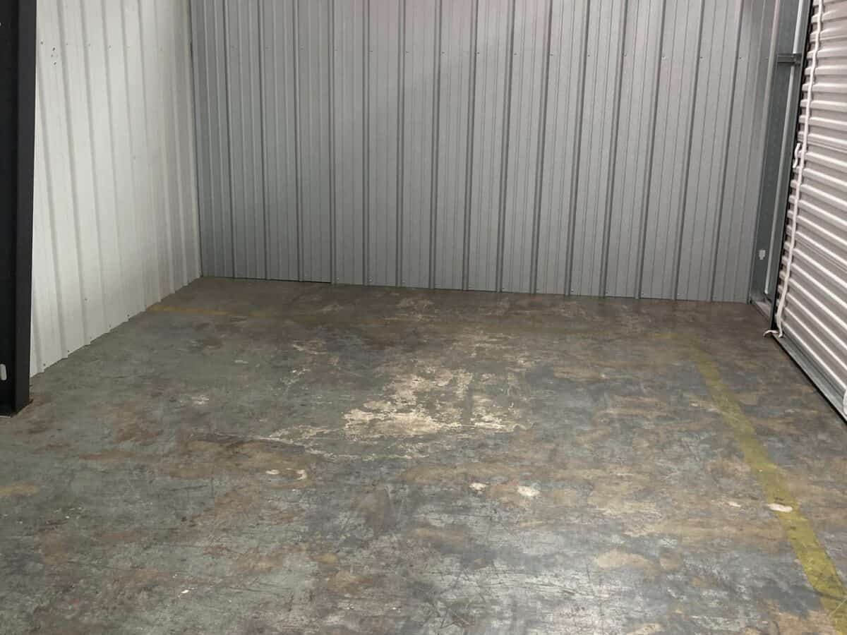 A small empty room with a concrete floor and a metal wall.