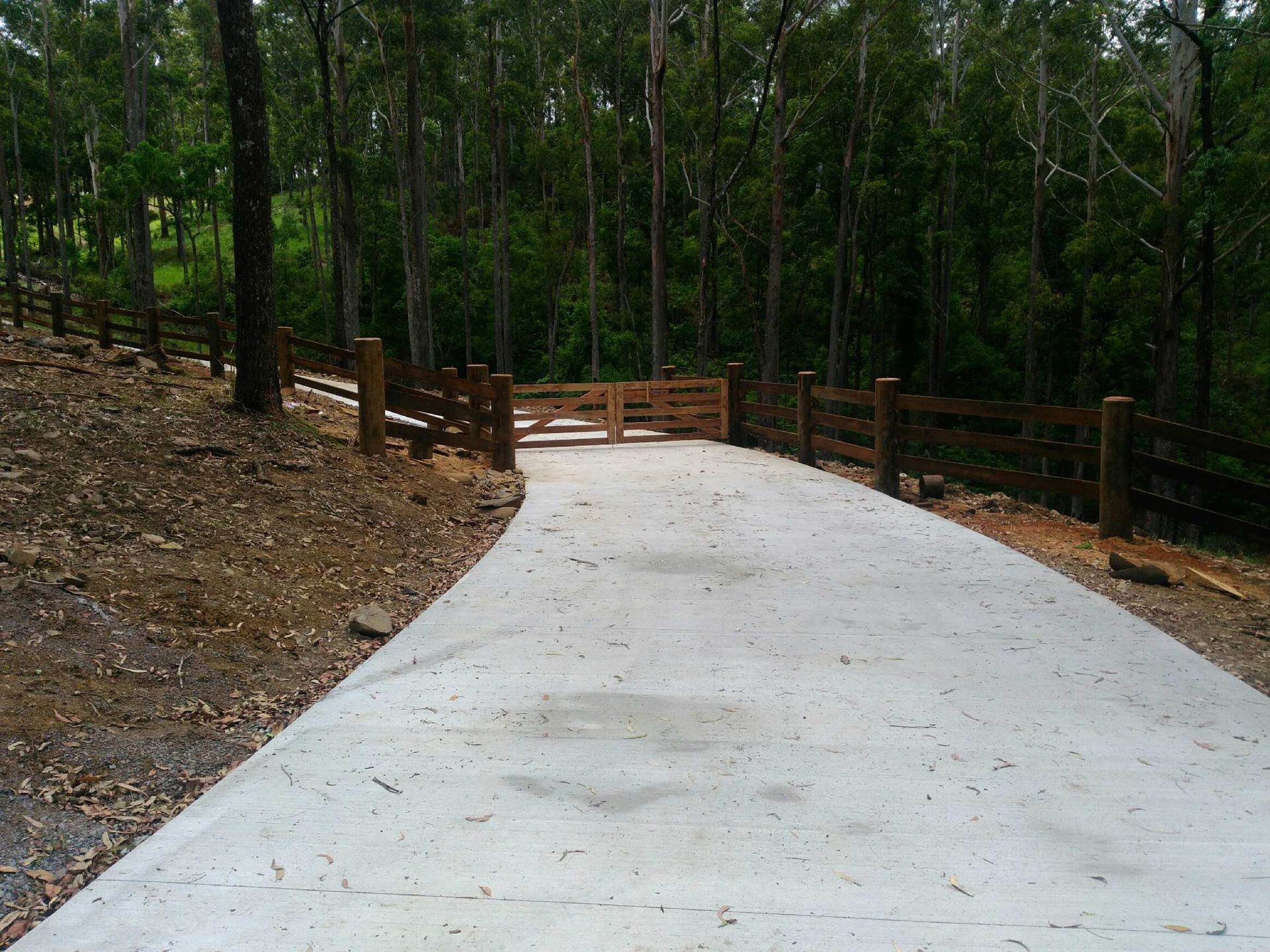 A Driveway With A Wooden Fence And Trees On Both Sides — John Stark Fencing In West Woombye, QLD