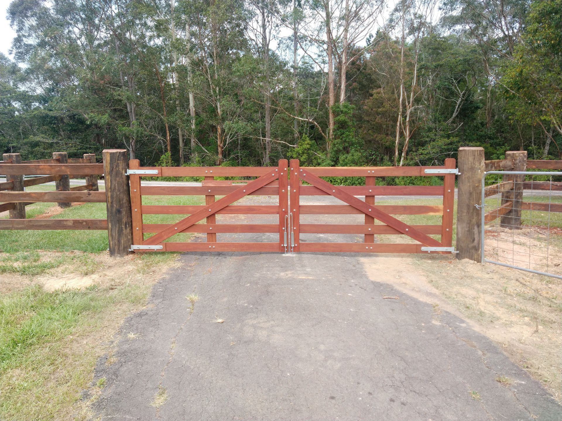 A Wooden Fence With A Gate and A Forest In The Background — John Stark Fencing In West Woombye, QLD