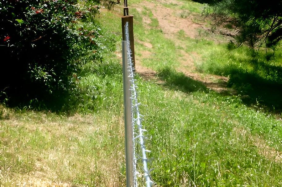 A Metal Pole Is Sitting In The Middle Of A Grassy Field — John Stark Fencing In Nambour, QLD