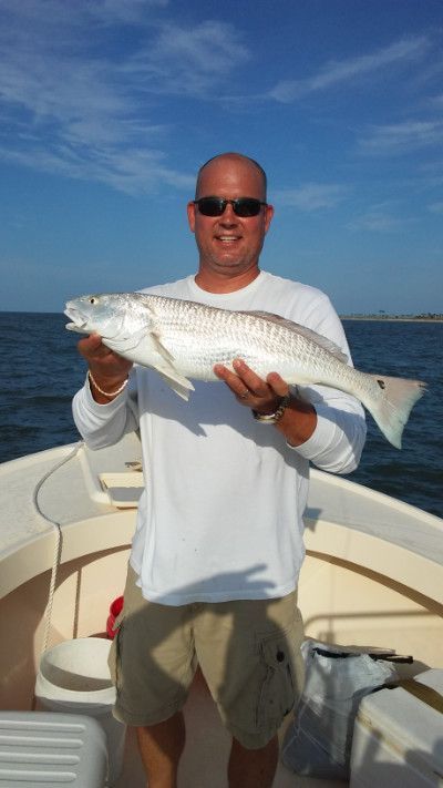 Man holding a large silver fish on a boat under a blue sky