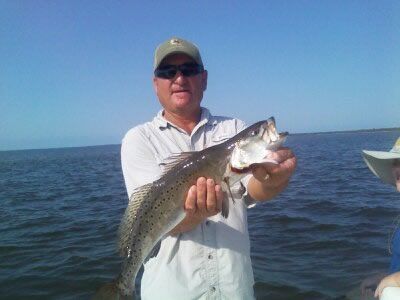 Man on a boat holds up a large striped fish over open water