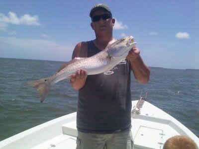 Person on a boat holding a large fish on open water under a blue sky