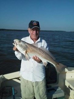Man holding a large fish on a boat, with open water in the background.