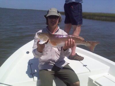 Person on a boat holding a large fish on a sunny body of water.