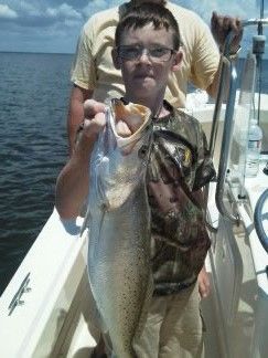Person on a boat holding up a large fish over the ocean.