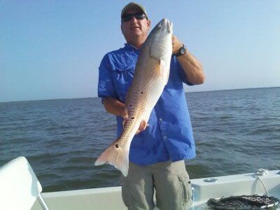 Man holding a large fish on a boat at sea under a clear blue sky