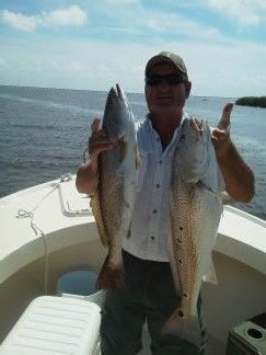 Person on a boat holding two large fish on a sunny day on the water