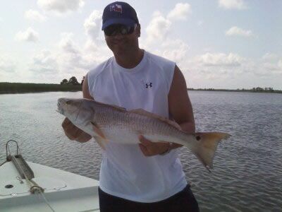 Man holding a large fish on a boat with calm water and cloudy sky in the background