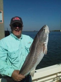 Man holding a large silver fish on a boat, with blue water and sky in the background.