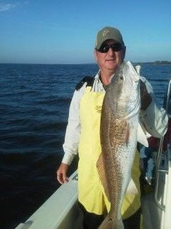 Angler on a boat holding a large fish against a blue ocean background