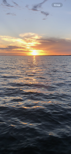 Sunset over a calm ocean, with golden light reflecting on rippling water.