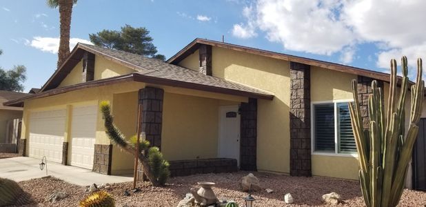 Yellow house with brown trim and stone accents.