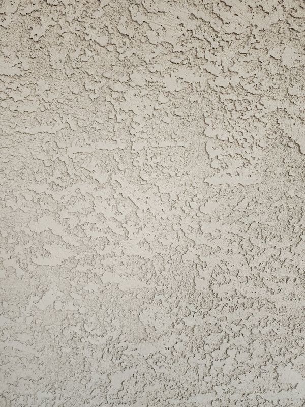 Textured stucco wall, light beige with irregular patterns.
