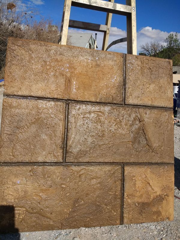 A rectangular panel with textured brown rectangular blocks separated by dark lines, leaning against a wooden structure.