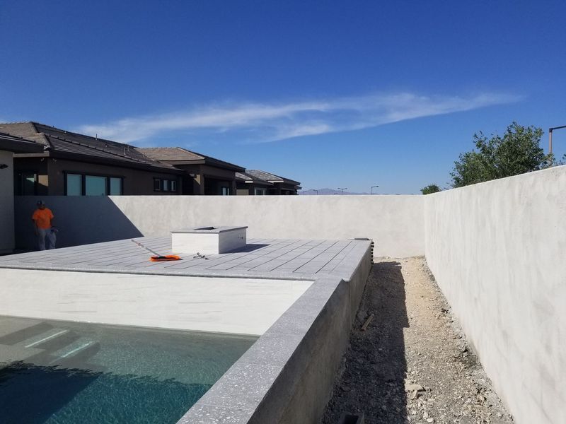 Backyard pool area with fire pit, concrete walls, and clear sky.
