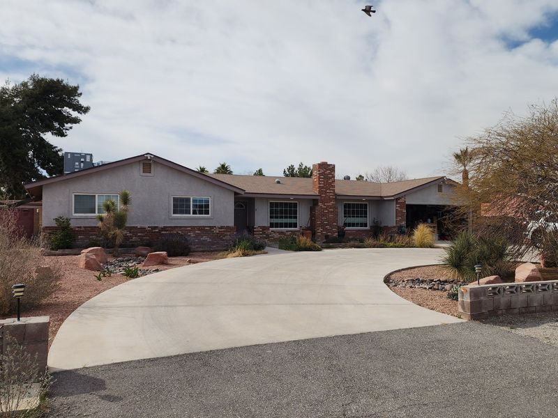 Single-story home with a long driveway on a sunny day. 