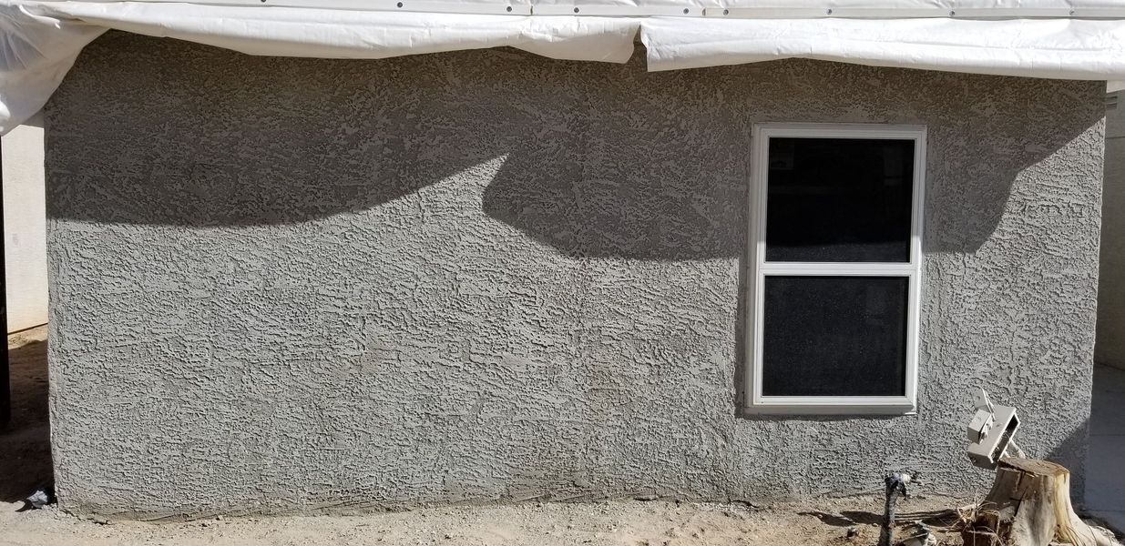Gray stucco wall with a white-framed window. 