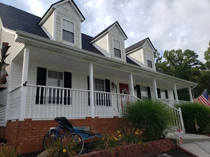 A house with a large porch and a motorcycle parked in front of it