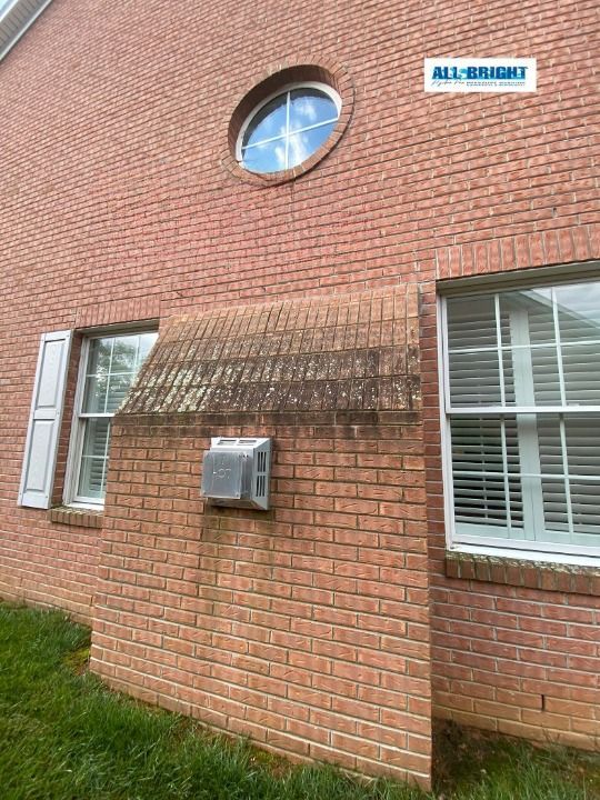 A red brick house with a round window and white shutters.