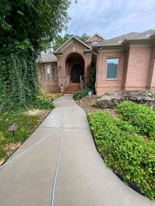 A brick house with a concrete walkway leading to it.
