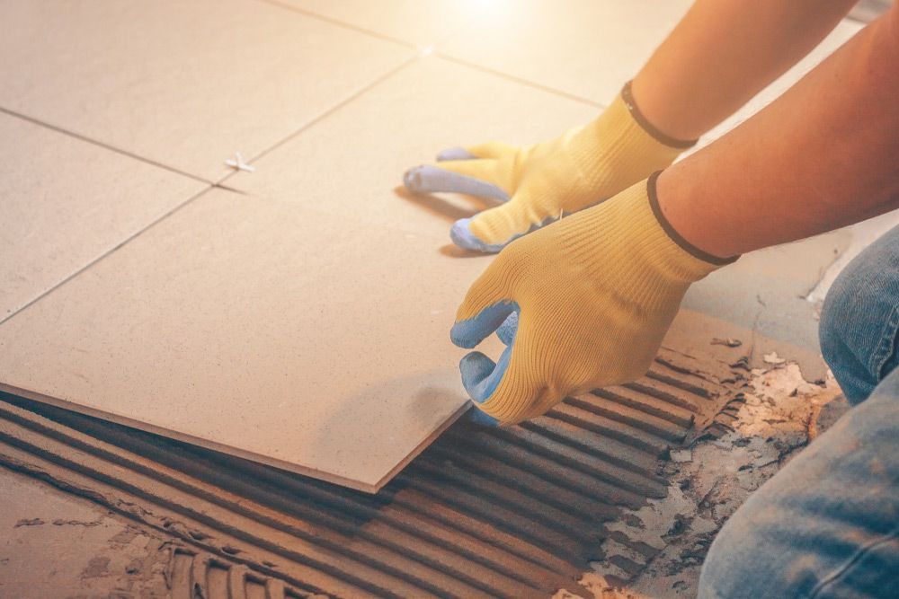 A Person Is Laying A Tile On The Floor — Affordable Carpets Woolgoolga In Woolgoolga, NSW