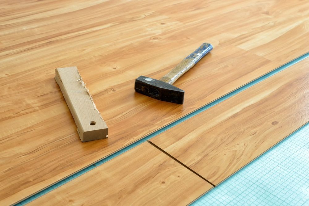 A Hammer And A Saw Are Laying On A Wooden Floor — Affordable Carpets Woolgoolga In Grafton, NSW