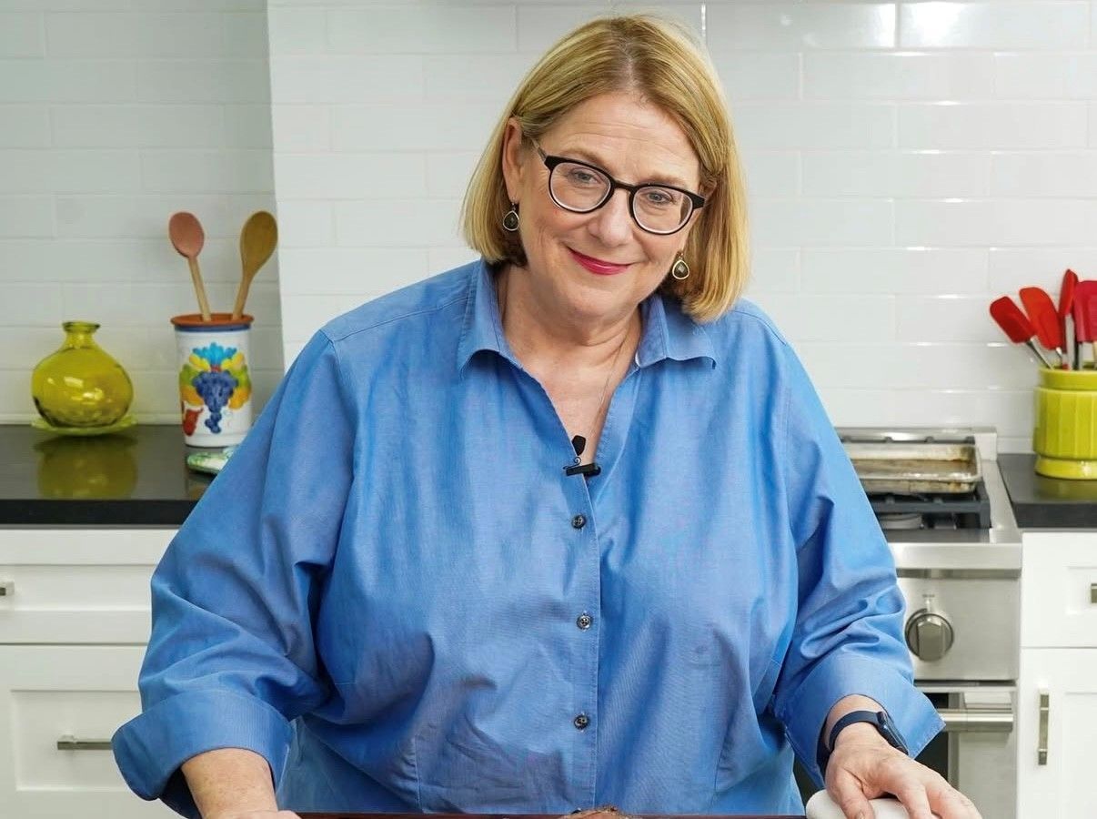 Woman in blue shirt, smiling, in a kitchen.