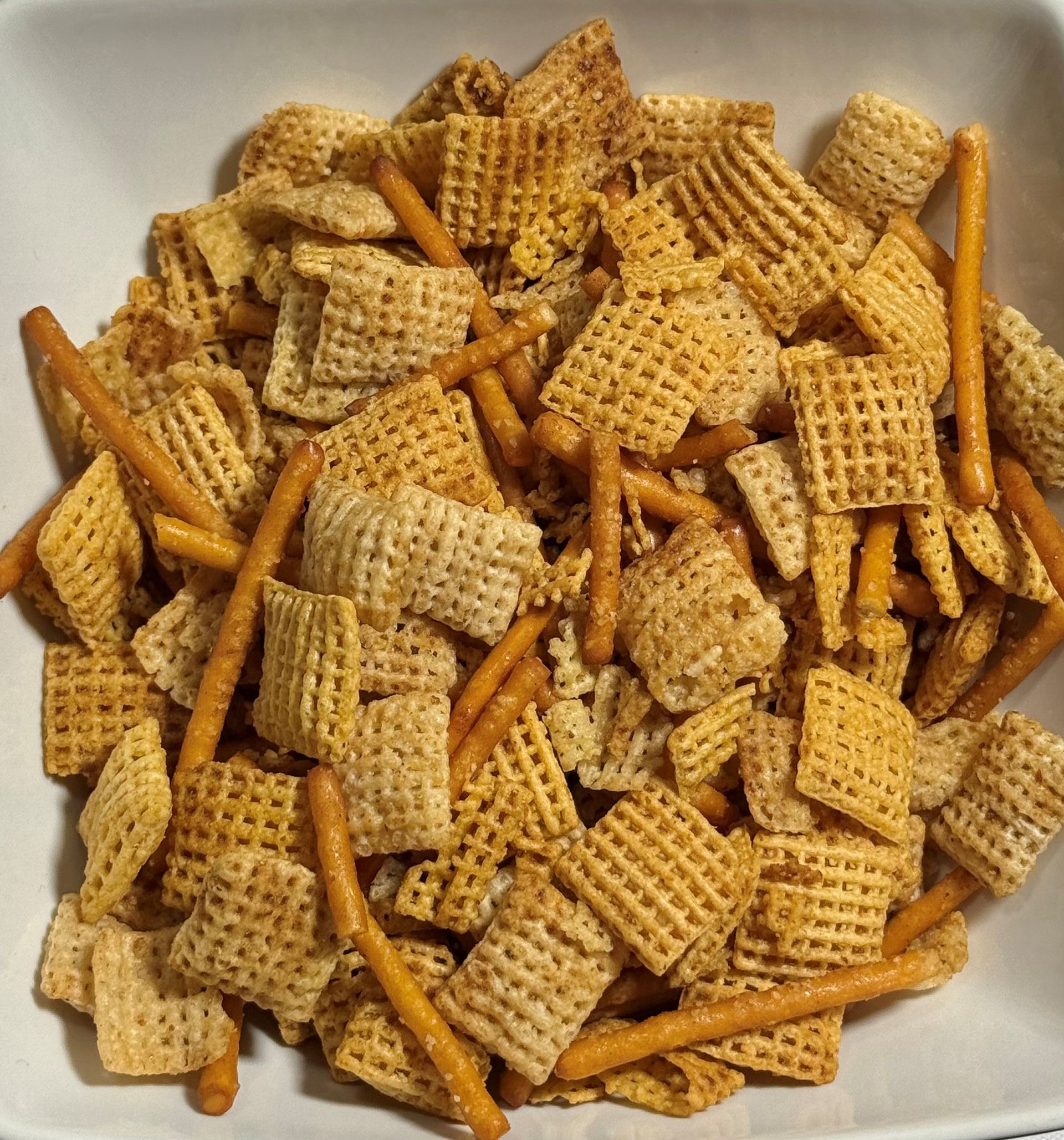 A bowl of Chex mix with cereal squares and pretzel sticks.