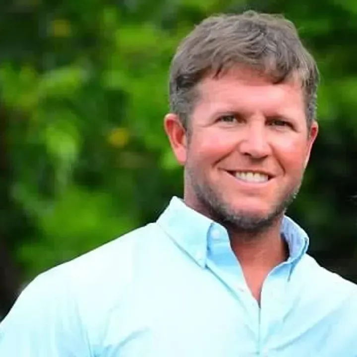 A man in a blue shirt is smiling for the camera.