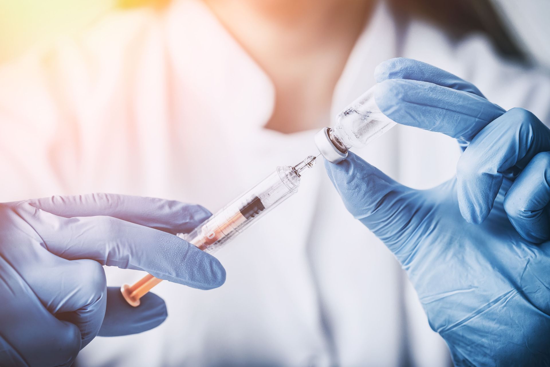 Um médico está segurando uma seringa e um frasco de vacina.