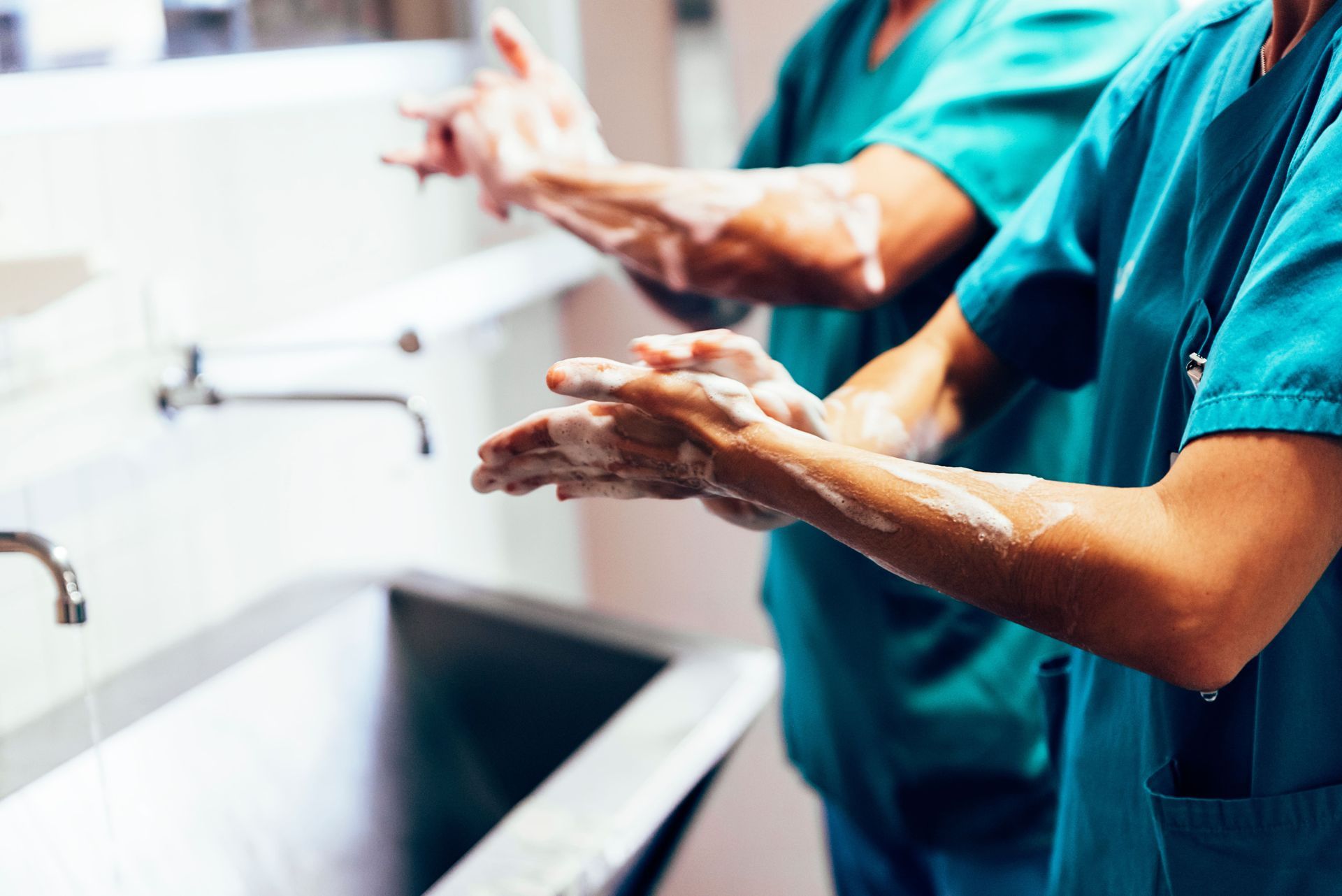 Duas enfermeiras lavam as mãos na pia do hospital.
