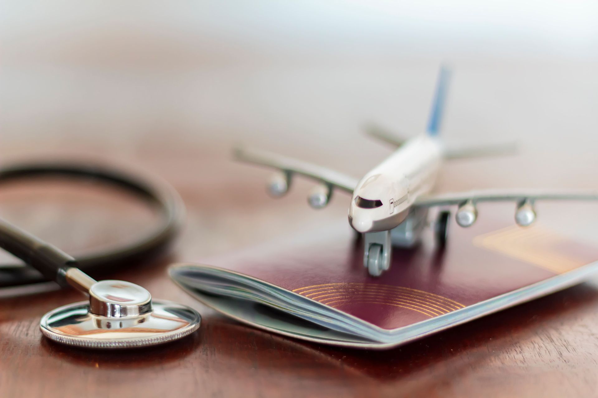 Um avião de brinquedo está em cima de um passaporte ao lado de um estetoscópio.