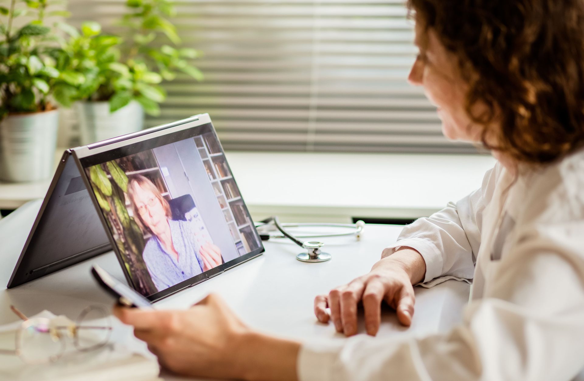 Um médico está fazendo uma videochamada com um paciente em um laptop.