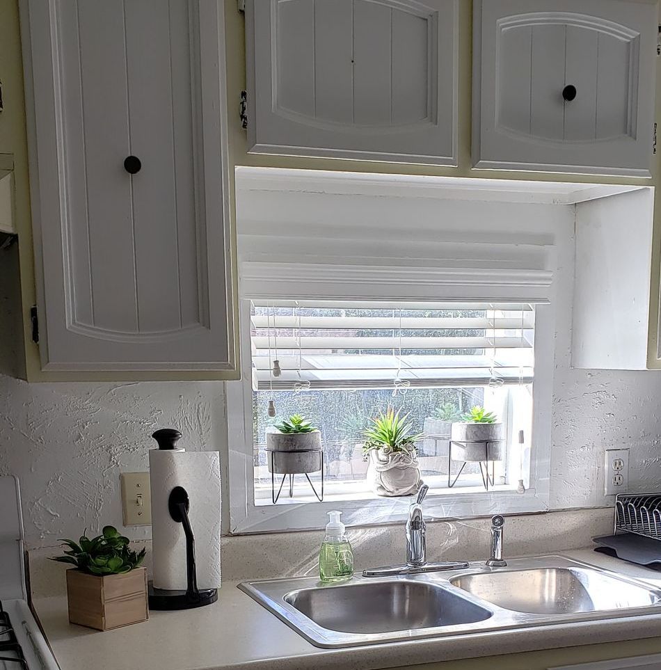 white wooden blinds with plants hanging over the kitchen