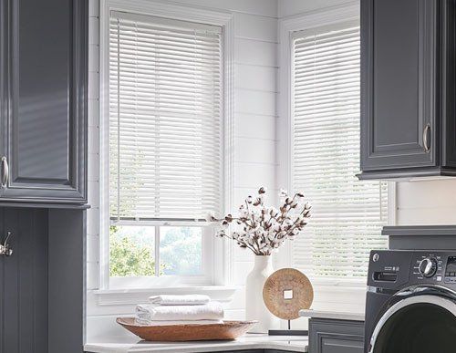a laundry room with a washer and dryer and a window with Aluminum blinds .